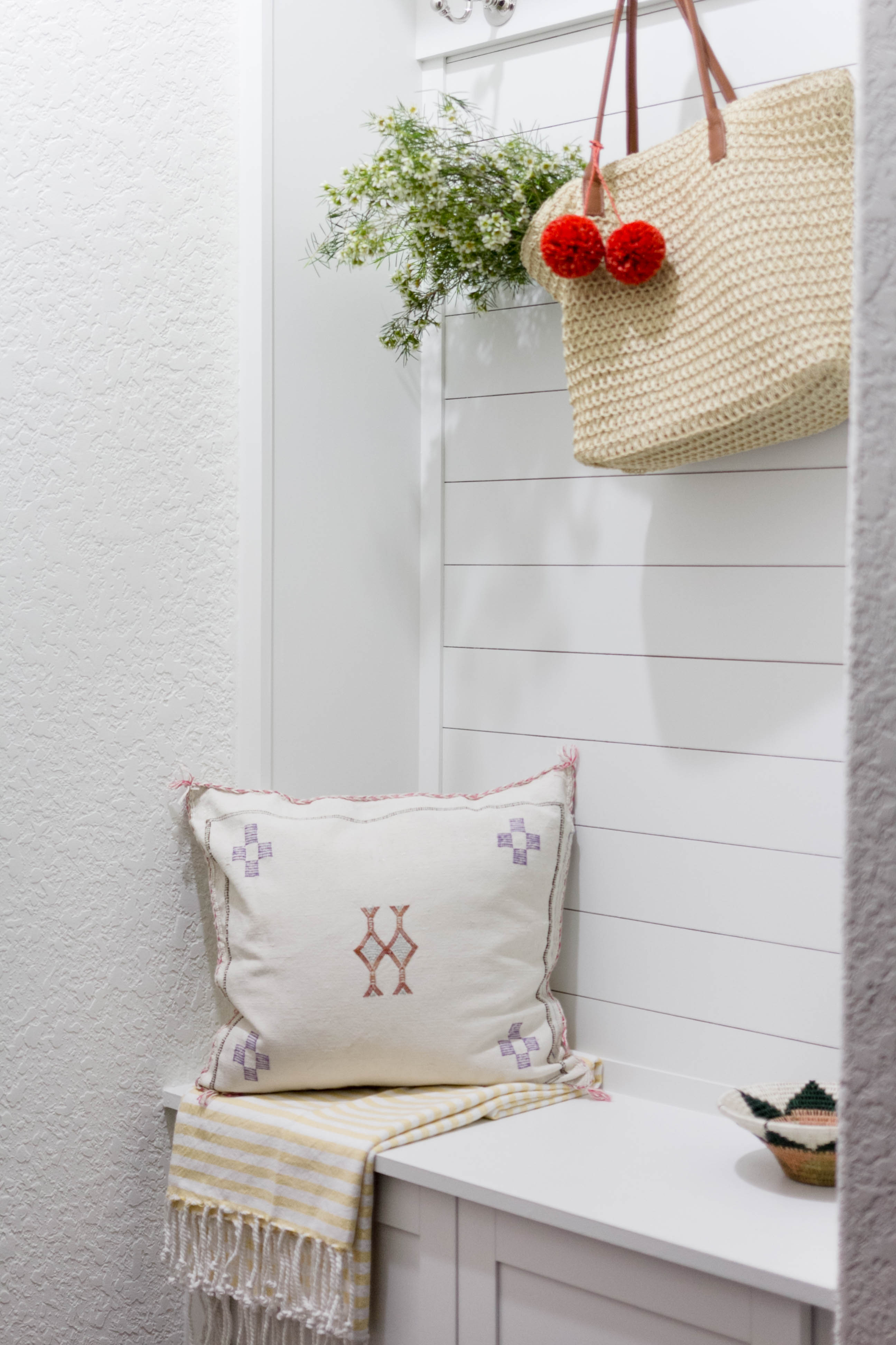 Built-in seating/storage in a bright and welcoming mudroom/powder room combo with a modern-casual-beach feel. Designed by: IrisNacole.com