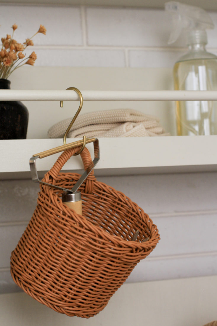 Small woven basket hanging from "s" hook in laundry room.