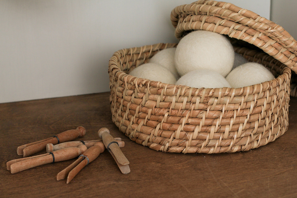 Wool laundry balls, stored on wooden counter top, in woven basket with lid.
