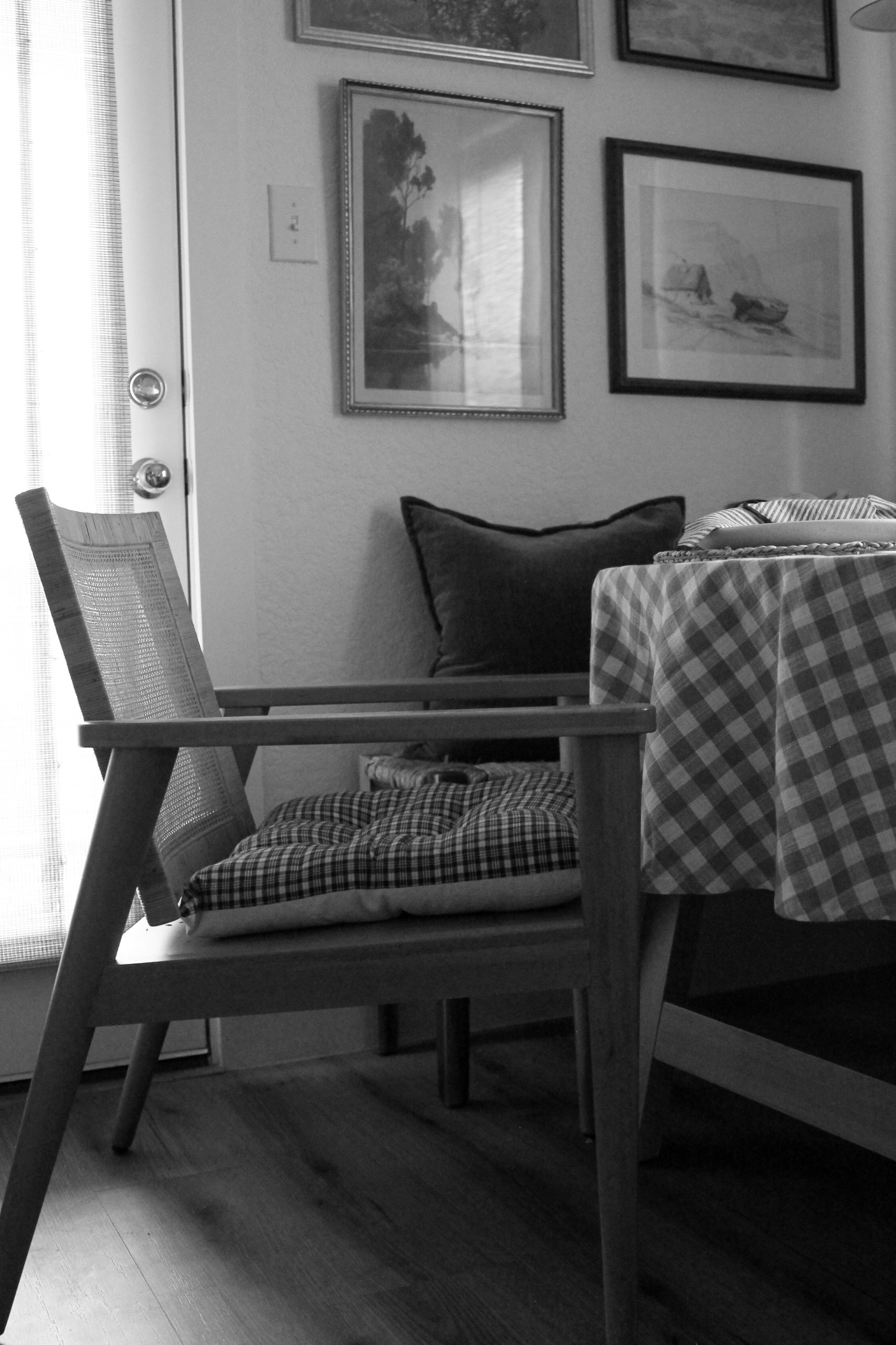 Table setting, mcm style chair with round table featuring a gingham tablecloth.