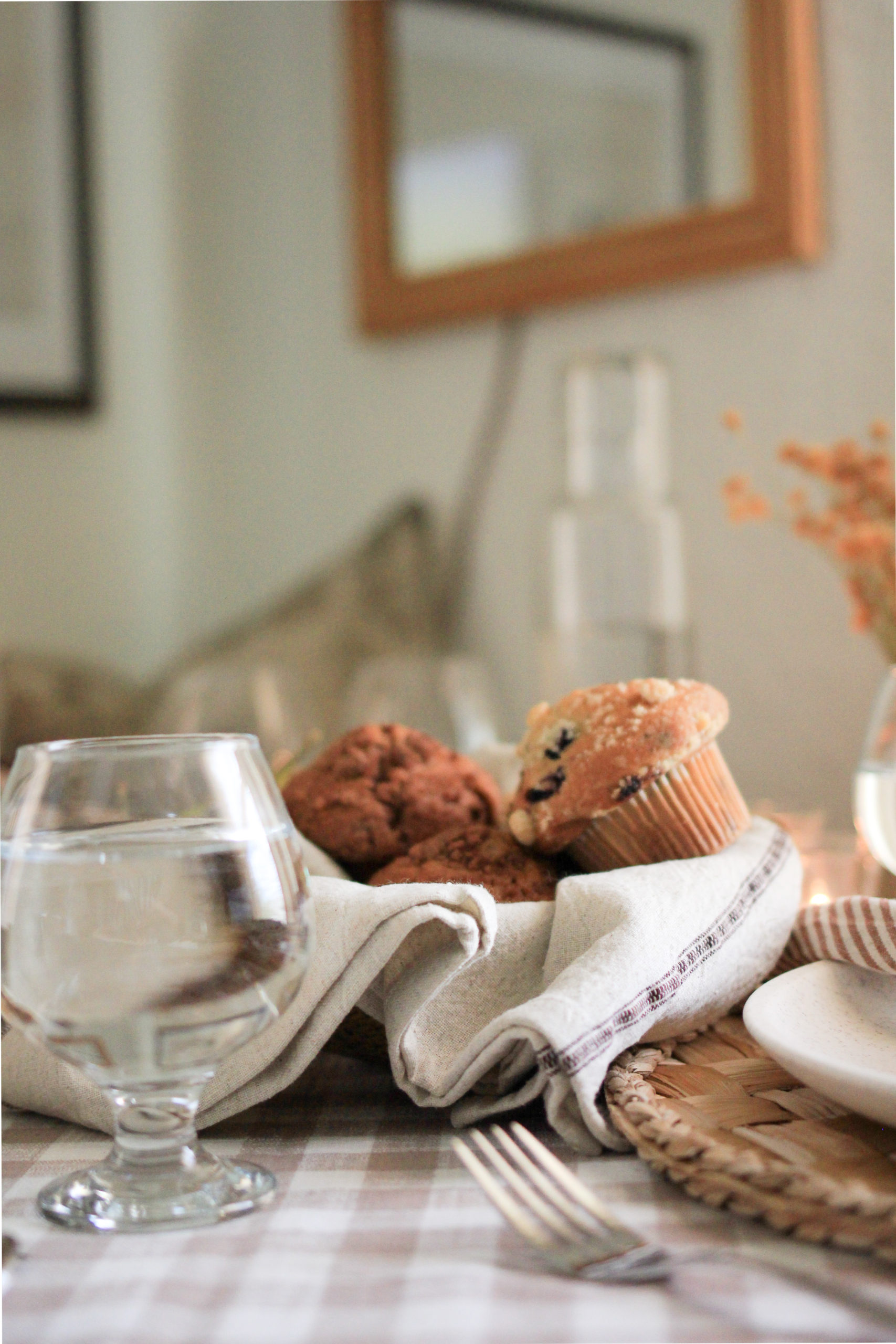 Table setting, woven basket with hand towel filler holding assorted muffins.