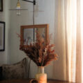 Styled for fall, a rattan cornucopia basket with dried grasses displayed on a dining table. Styling by Iris Nacole