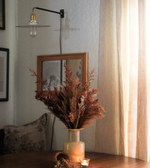 Styled for fall, a rattan cornucopia basket with dried grasses displayed on a dining table. Styling by Iris Nacole