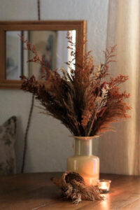 Styled for fall, a rattan cornucopia basket with dried grasses displayed on a dining table. Styling by Iris Nacole