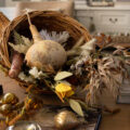 Coffee table styled for autumn/fall. Dripping tapered candles, and woven cornucopia, filled with gourds and fall foliage.