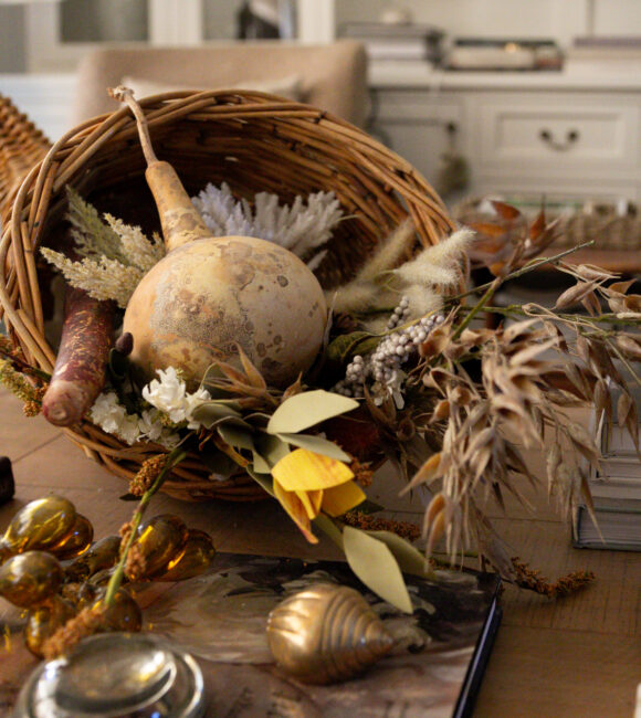 Coffee table styled for autumn/fall. Dripping tapered candles, and woven cornucopia, filled with gourds and fall foliage.